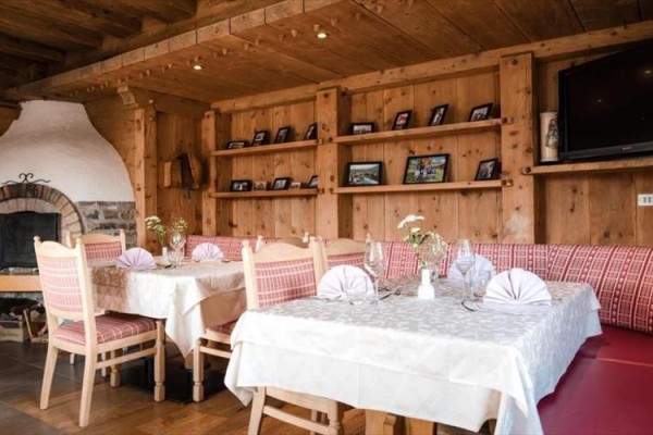 Stylová restaurace s dřevěným interiérem, připravenými stoly a krbem.
