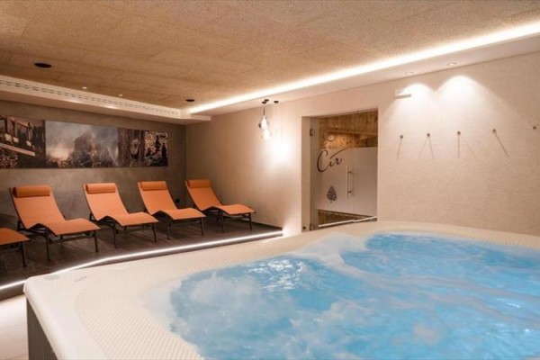 Vířivka a oranžová lehátka v moderní relaxační místnosti.