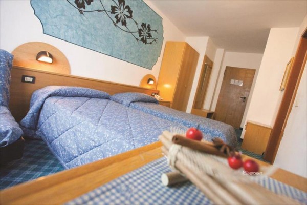 Hotelový pokoj s dvěma samostatnými postelemi a modrým dekorem na zdi.