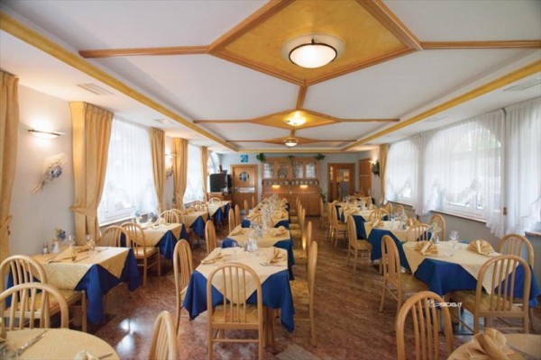 Elegantní interiér restaurace s dřevěným nábytkem a modro-béžovými ubrusy.