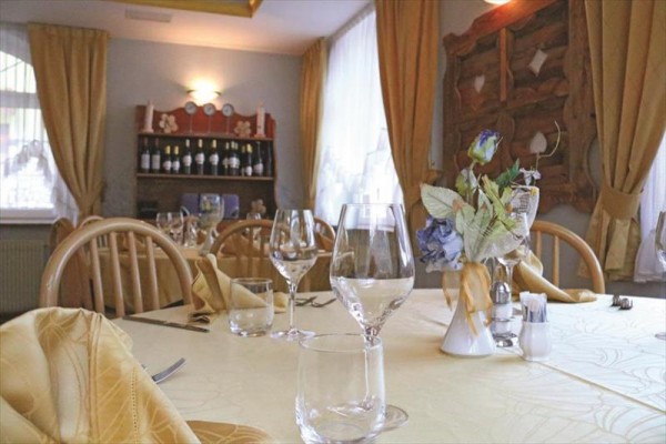 Restaurace s elegantně prostřeným stolem, skleničkami a květinovou ozdobou.