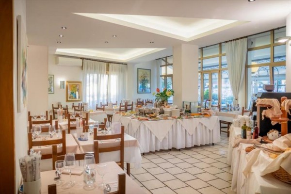 Restaurace s prostřenými stoly a bufetovým stolem uprostřed.