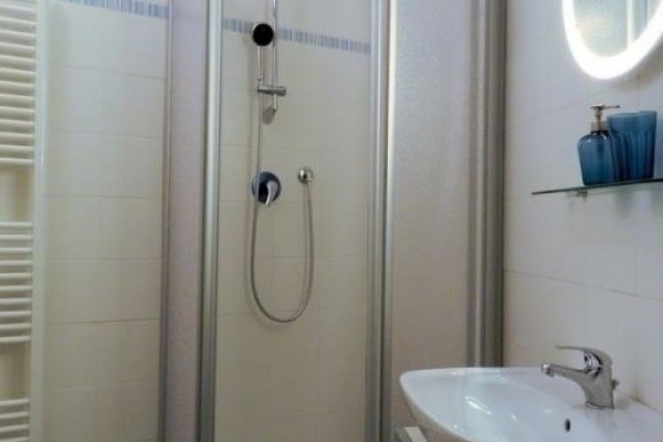 Moderní koupelna se sprchovým koutem, umyvadlem a zrcadlem.