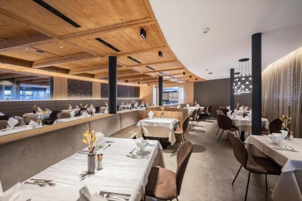 Restaurace s elegantně prostřenými stoly a dřevěným stropem.