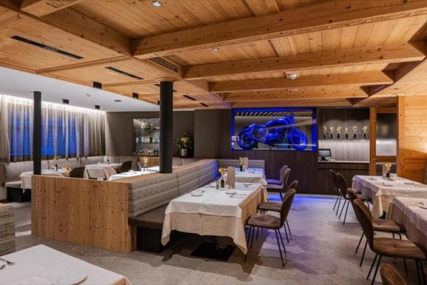 Moderní restaurace s dřevěným interiérem a vystavenou modrou motorkou.