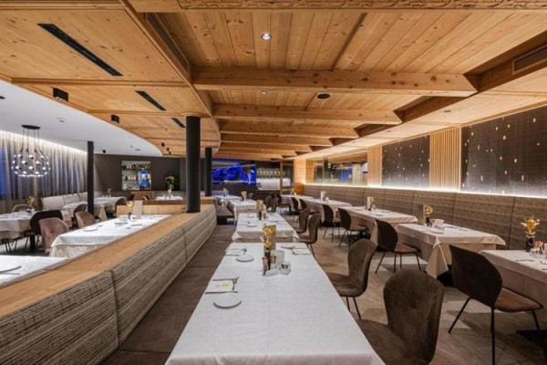 Moderní restaurace s dřevěným stropem a stolky pokrytými bílými ubrusy.