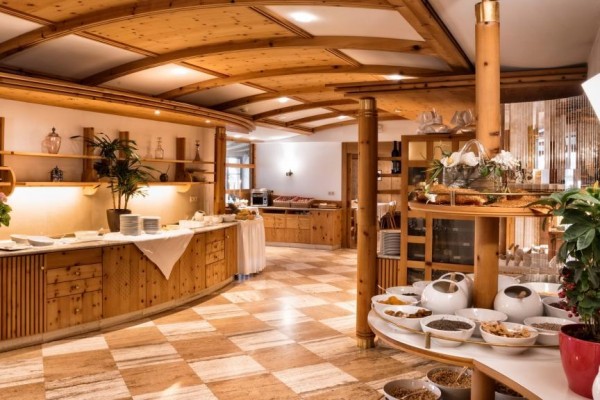Interiér hotelové restaurace s dřevěným nábytkem a snídaňovým bufetem.