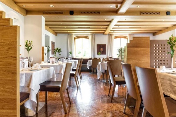 Interiér restaurace s prostřenými stoly a dřevěným stropem.