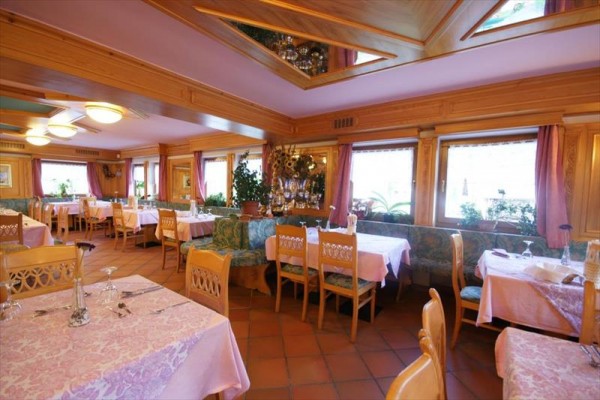Restaurace s dřevěným interiérem, prostřenými stoly a růžovými ubrusy.