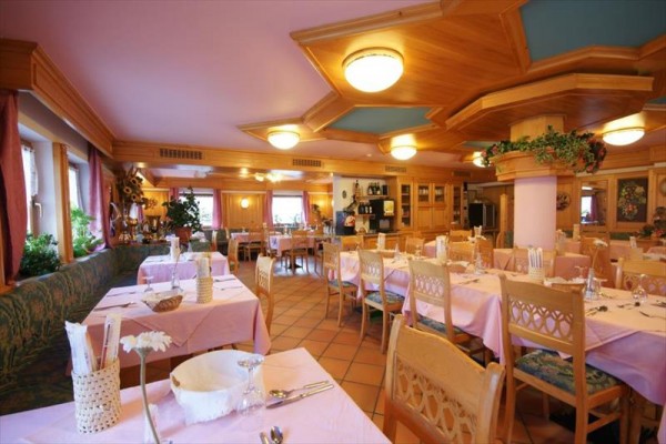 Prostorná restaurace s dřevěným nábytkem a růžovými ubrusy.