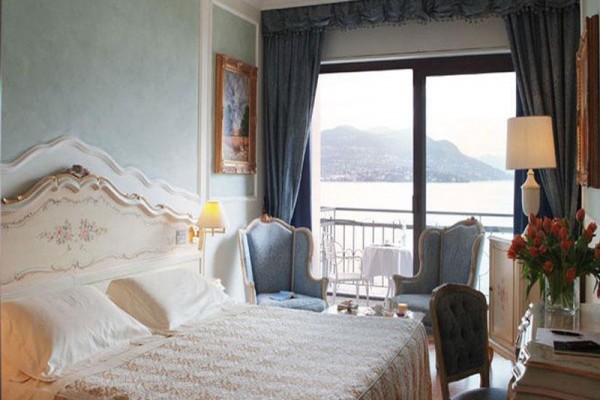 Luxusní hotelový pokoj s výhledem na jezero a horami, vybavený elegantním nábytkem.