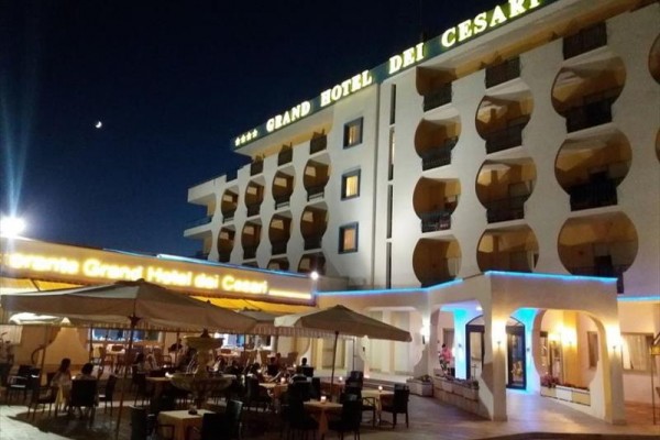 Večerní pohled na osvětlený Grand Hotel dei Cesari s venkovní restaurací.