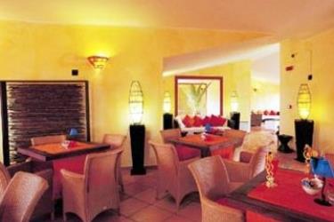 Interiér restaurace se žlutými stěnami, ratanovými židlemi a tlumeným osvětlením.
