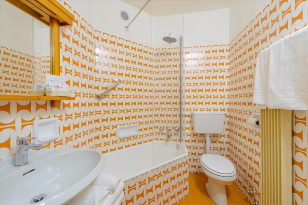Retro koupelna s oranžovými obklady a vanou.