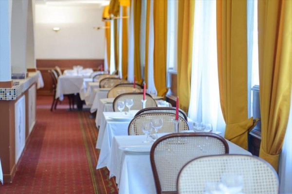 Elegantní restaurace s prostřenými stoly a žlutými závěsy.