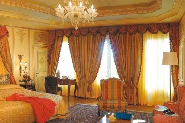 Luxusní pokoj s bohatými závěsy, lustry a elegantním nábytkem.