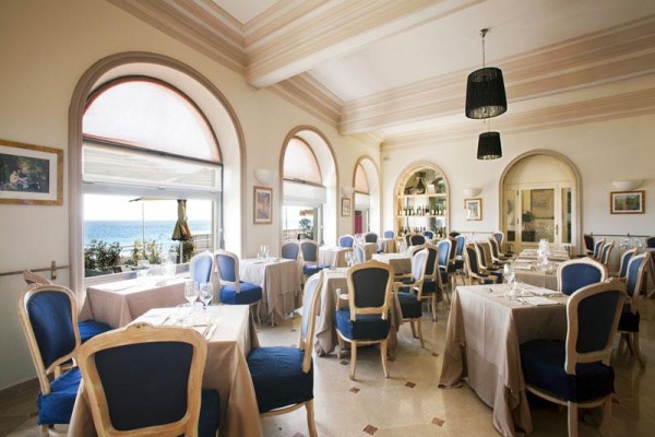 Elegantní restaurace s modrými židlemi a výhledem na moře.