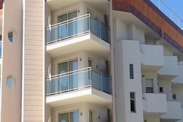 Moderní budova s balkonem a modrými skleněnými zábradlími.