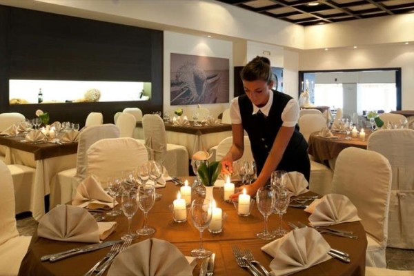 Číšnice připravuje stůl se zapálenými svíčkami v elegantní restauraci.