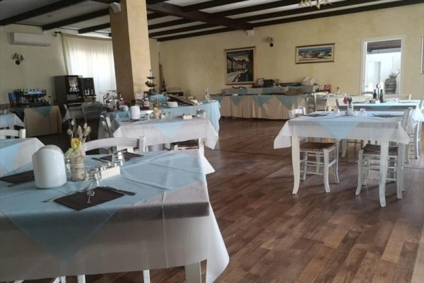 Restaurace s dřevěnou podlahou a modro-bílými ubrusy na stolech.