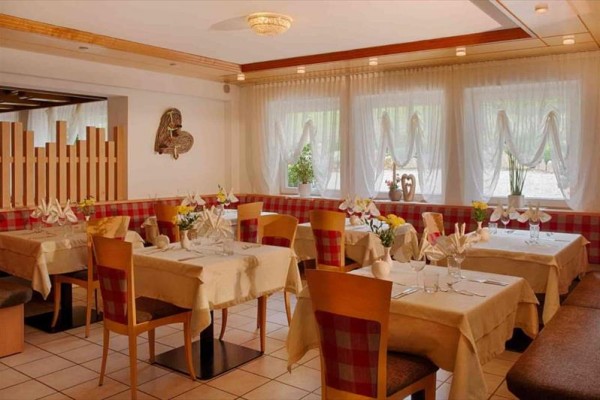 Útulná restaurace s prostřenými stoly a červenobílými kostkovanými sedadly.