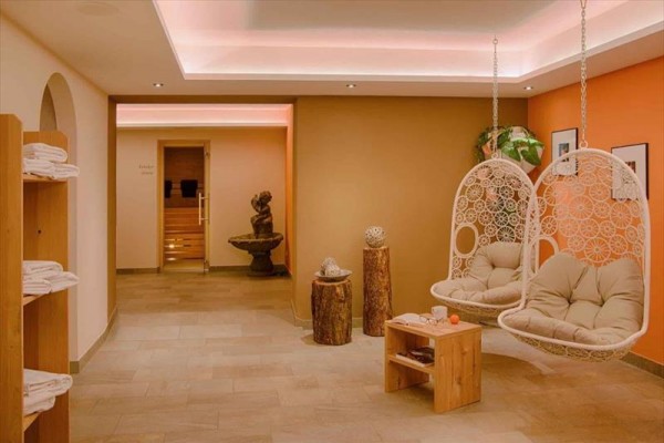 Interiér wellness s dvěma závěsnými křesly a dveřmi do sauny.