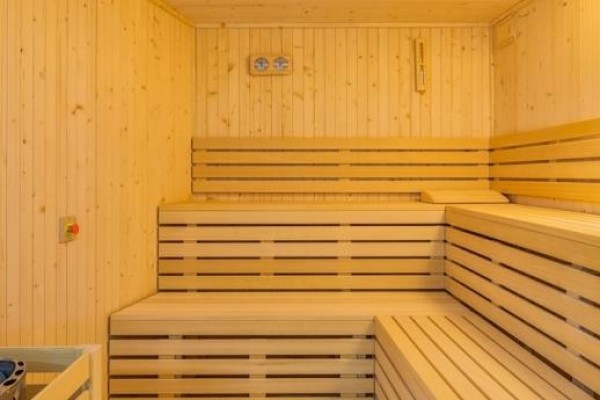 Dřevěná sauna s lavicemi a kamny.  