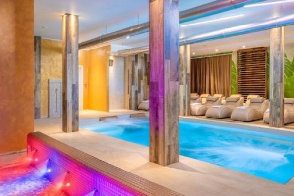 Moderní wellness centrum s bazénem a vířivkou obklopenou lehátky.