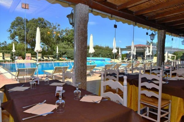 Krytá terasa restaurace s výhledem na bazén a lehátka.