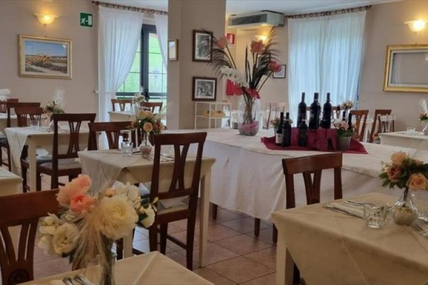 Restaurace s dřevěnými židlemi a stoly zdobenými květinovými aranžmá.