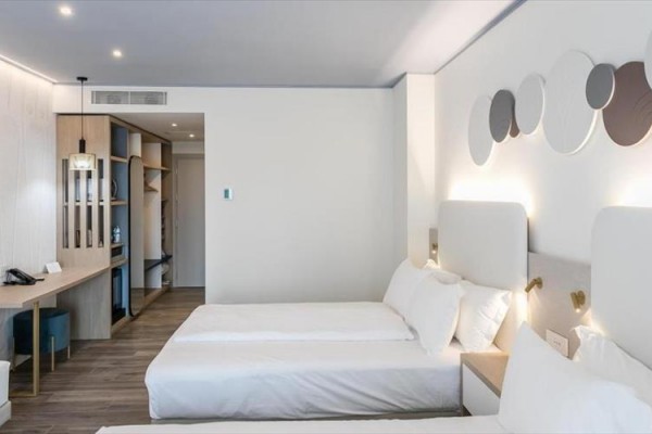 Moderní hotelový pokoj s dvěma bílými postelemi a jednoduchým designem.