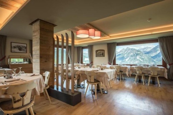 Elegantní restaurace s dřevěným nábytkem a velkým oknem s výhledem na hory.
