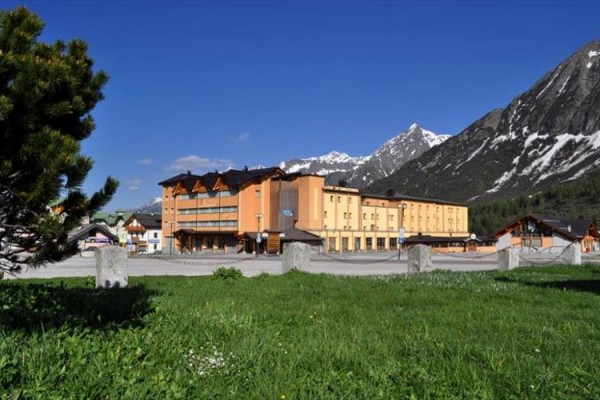 Hotel na louce s horskou krajinou v pozadí.