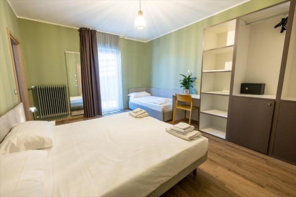 Moderně zařízená ložnice s manželskou postelí, jednolůžkem, šatníkem a zrcadlem.