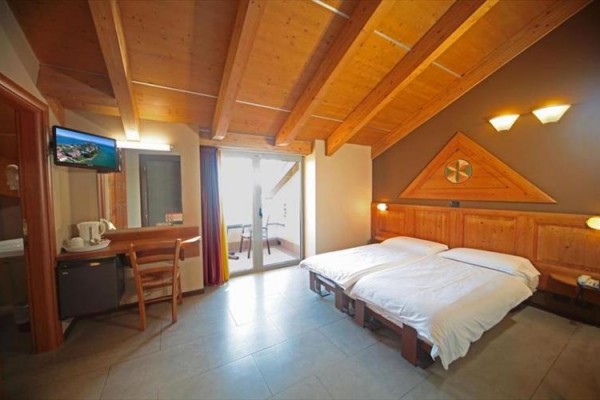 Pokoj s dvěma jednolůžky, dřevěným stropem a balkonem.