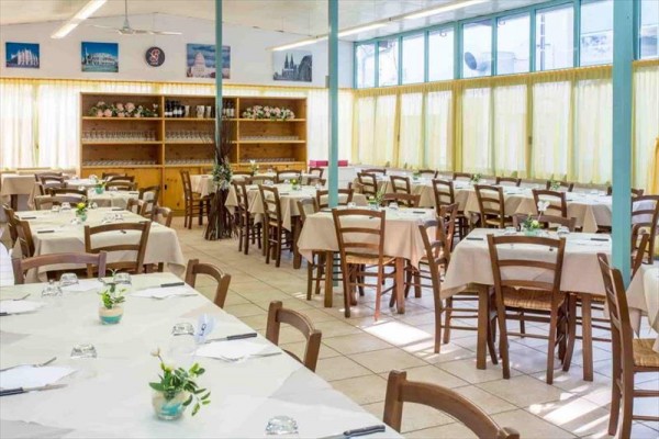 Restaurace se stoly a židlemi připravenými k servírování.