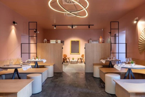 Moderní interiér restaurace s pastelově růžovými stěnami a kruhovými světly.