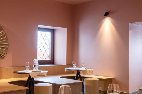 Moderní restaurace s růžovými zdmi a stylovým dřevěným nábytkem.