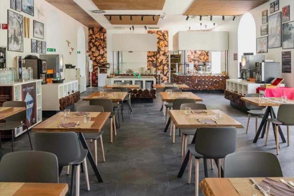 Moderní restaurace s dřevěnými stoly a obrazy na stěnách.