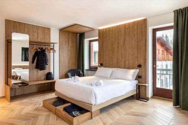 Moderní ložnice s dřevěným obložením, postelí a dveřmi na balkon.
