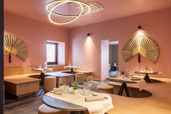 Moderní restaurace s kulatými stoly a dekoracemi na zdech.