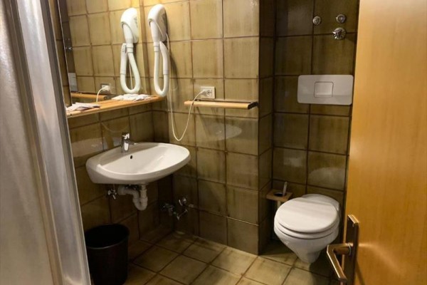 Koupelna s umyvadlem, toaletou a dvěma fénem na zdi.