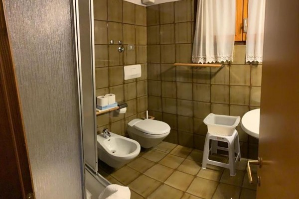 Koupelna s bidetem a toaletou, obložena hnědými kachličkami.