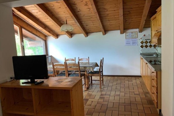 Dřevěný interiér kuchyně s jídelním stolem a televizí.