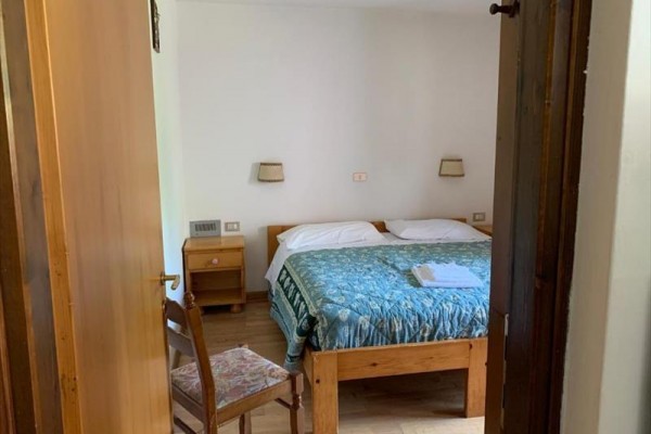 Pokoji dominuje manželská postel s modrým přehozem a vedlejším stolem s lampičkami.