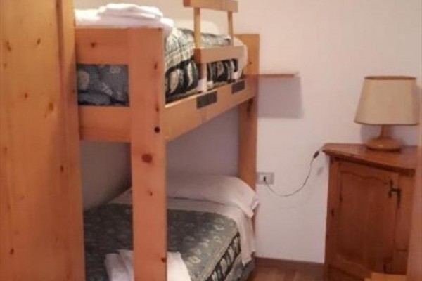 Palanda s dřevěným rámem vedle nočního stolku s lampou.