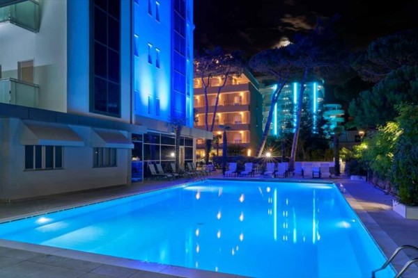 Noční pohled na osvětlený venkovní bazén u hotelu.