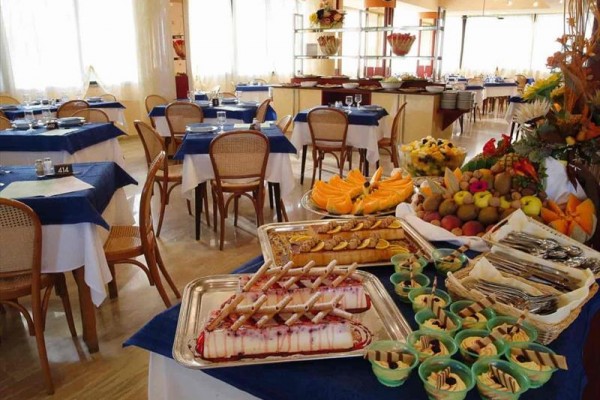 Bufetový stůl s dezerty a ovocem v restauraci s modrými ubrusy.