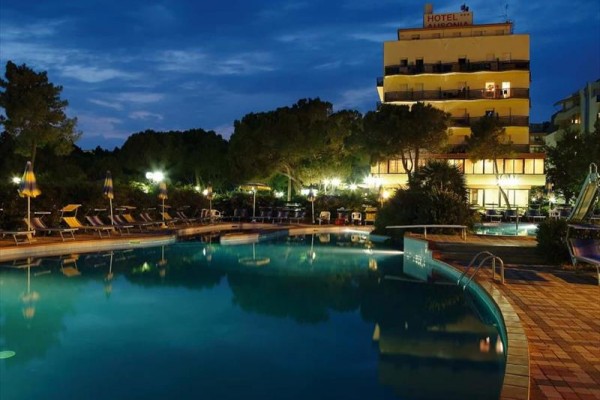 Osvětlený hotel a bazén v noci.