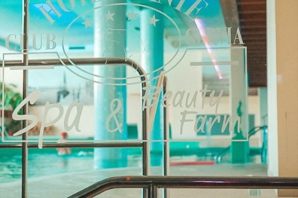 Skleněné dveře vedoucí k bazénu s nápisem Hotel Dante Spa & Beauty Farm.